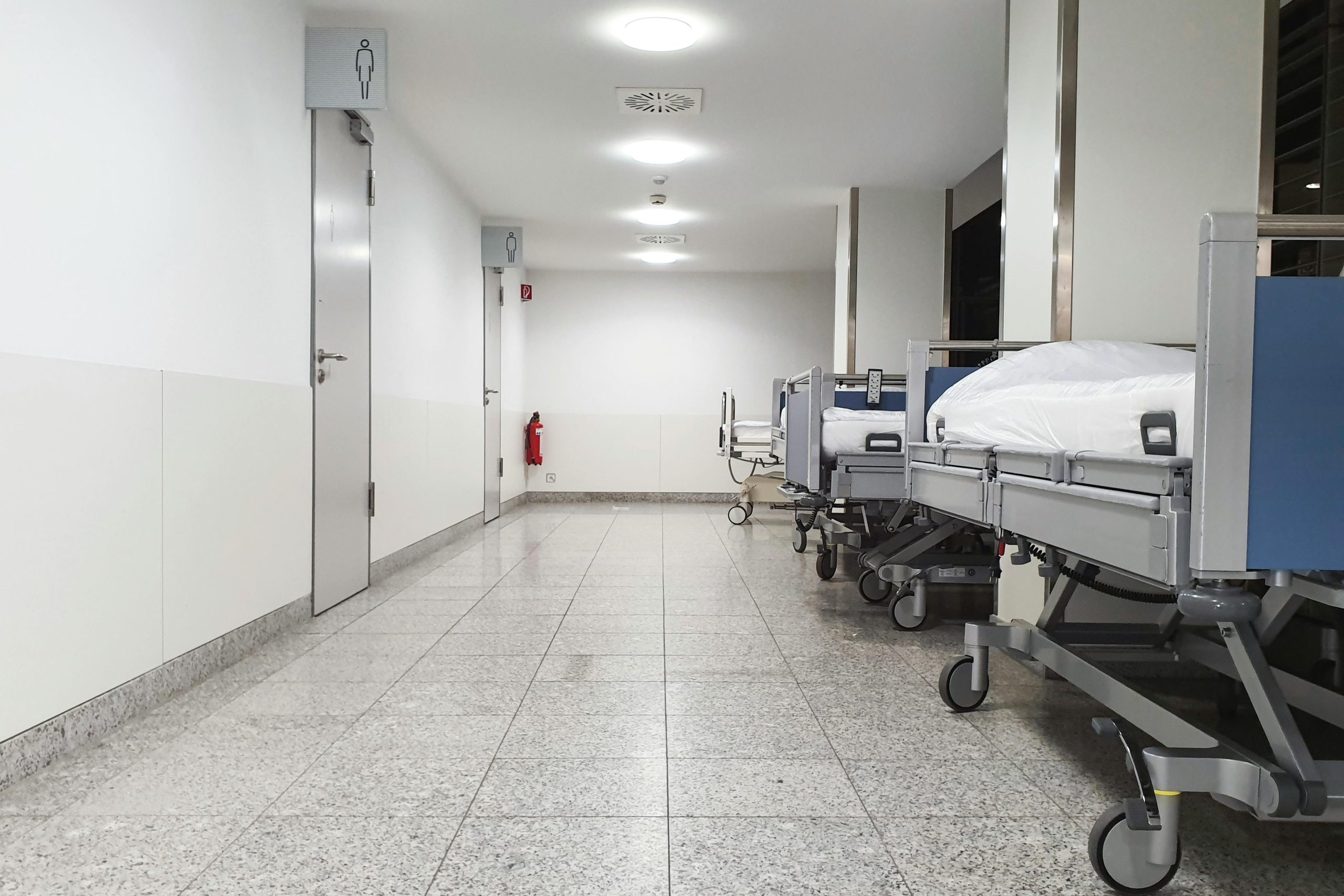 Modern hospital corridor with empty medical beds and sterile environment.